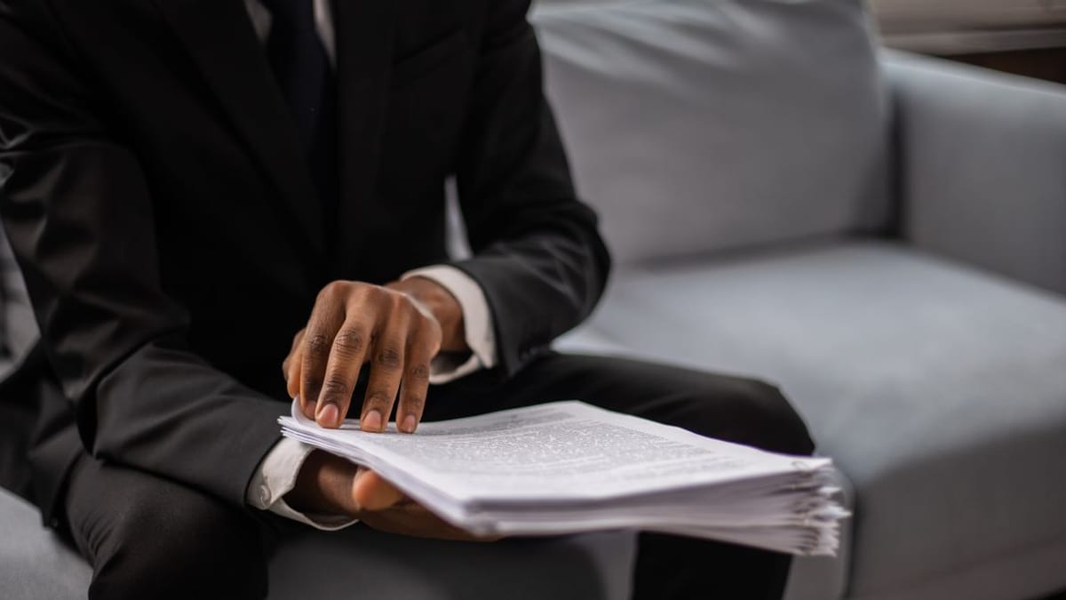 A person reading paperwork at a kitchen table