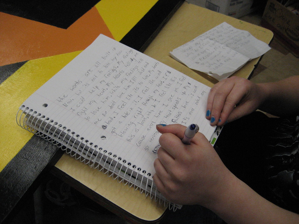 A laptop and notebook on a writing desk