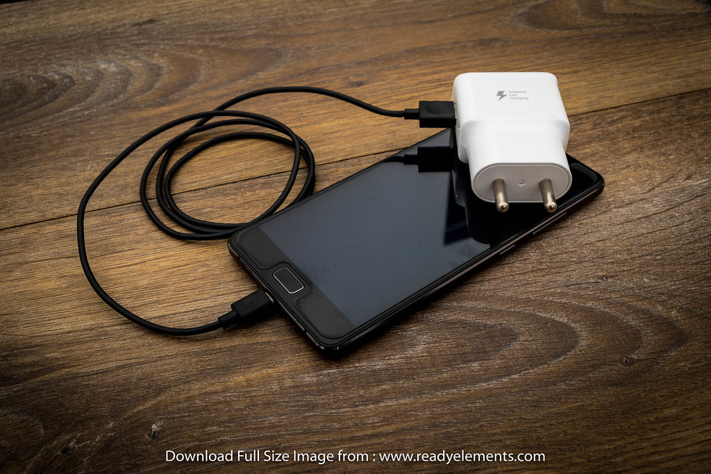 A phone charging on a desk with the battery health screen visible