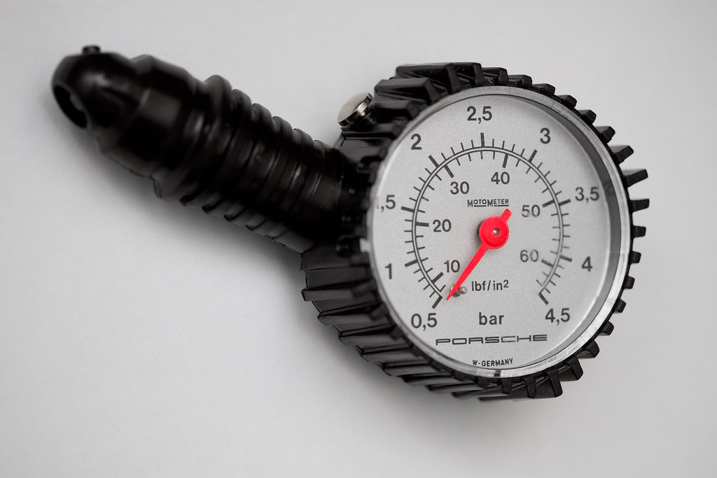 Un manomètre branché sur la valve d'un pneu de voiture