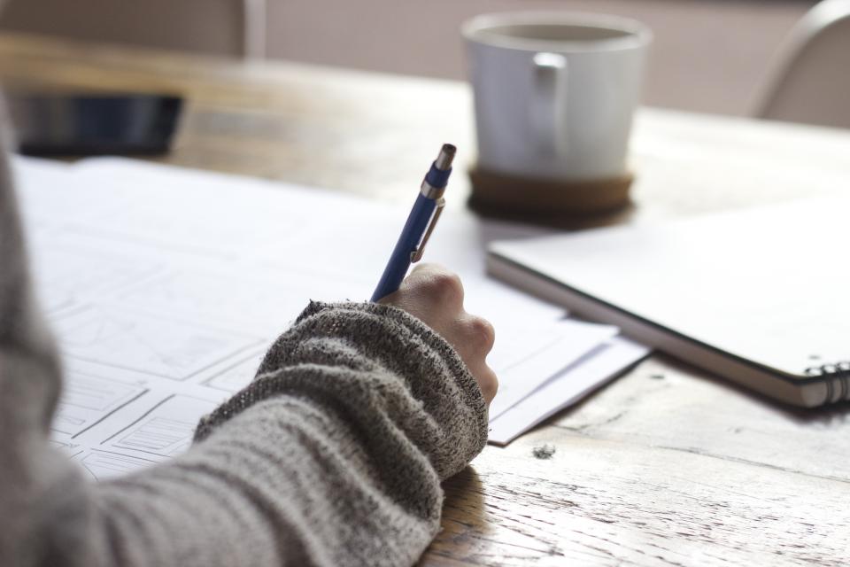 A notebook with a pen and coffee